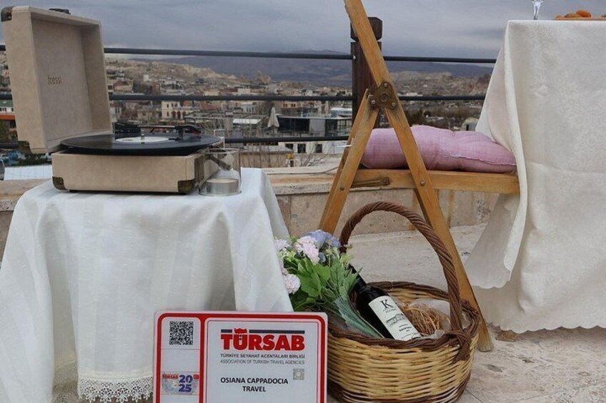 Una mesa con un tocadiscos, una cesta de mimbre con flores y un cartel con texto en turco. 3