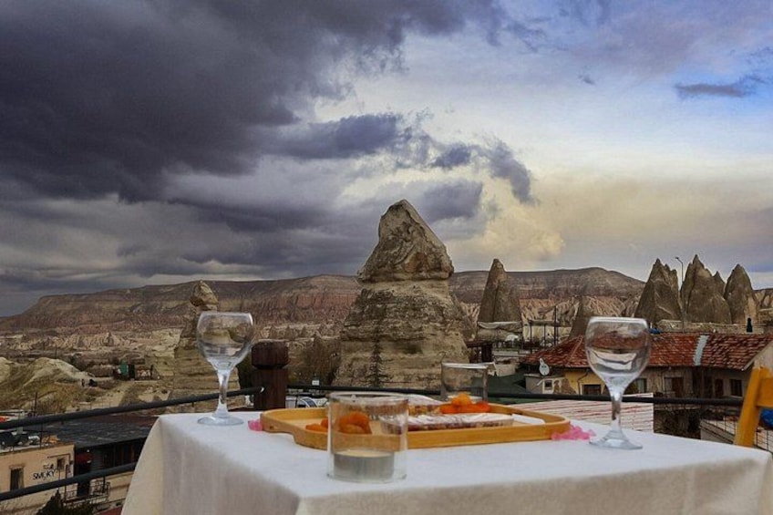 Une table dressée avec un repas et deux verres à vin, donnant sur un paysage montagneux. 4