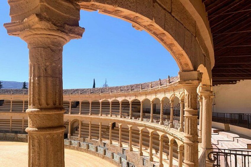 An ancient Roman amphitheater with stone arches and a clear blue sky. 1
