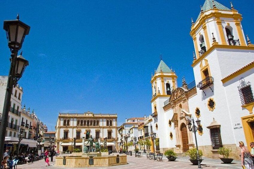 A plaza with a fountain, historic buildings, and a clear blue sky. 3
