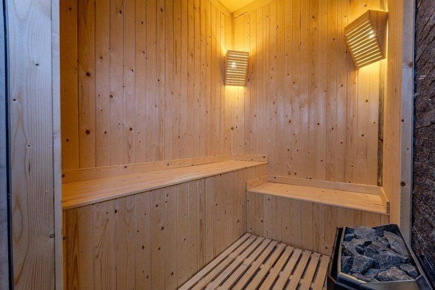 A wooden sauna with benches and wall-mounted lights. 5
