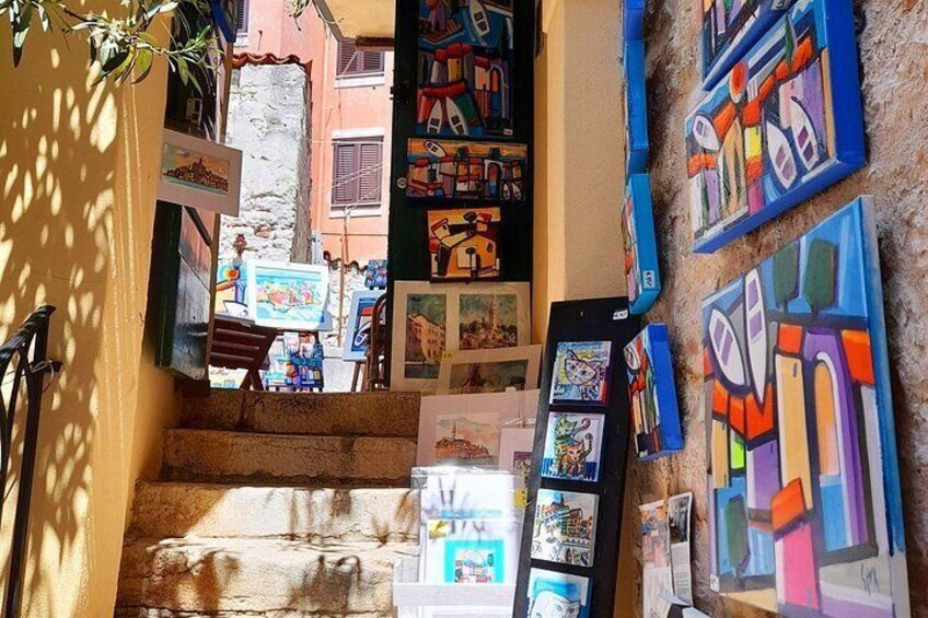 Un escalier dont les murs sont décorés de peintures colorées, avec une vue sur la rue en arrière-plan. 4