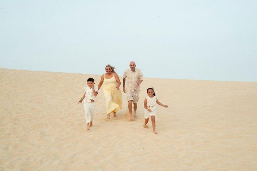 A family of four walking on a sandy beach. 4