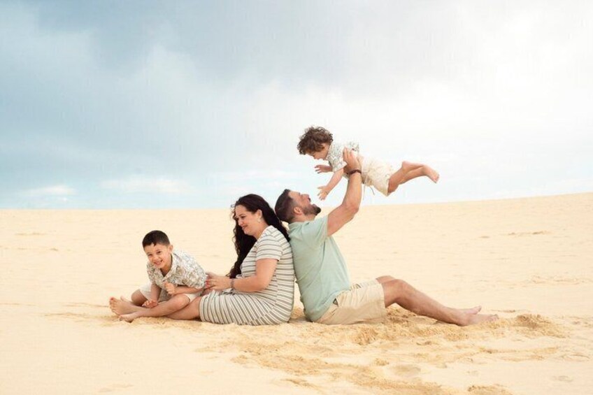 A family of three on a sandy beach with a clear sky. 1