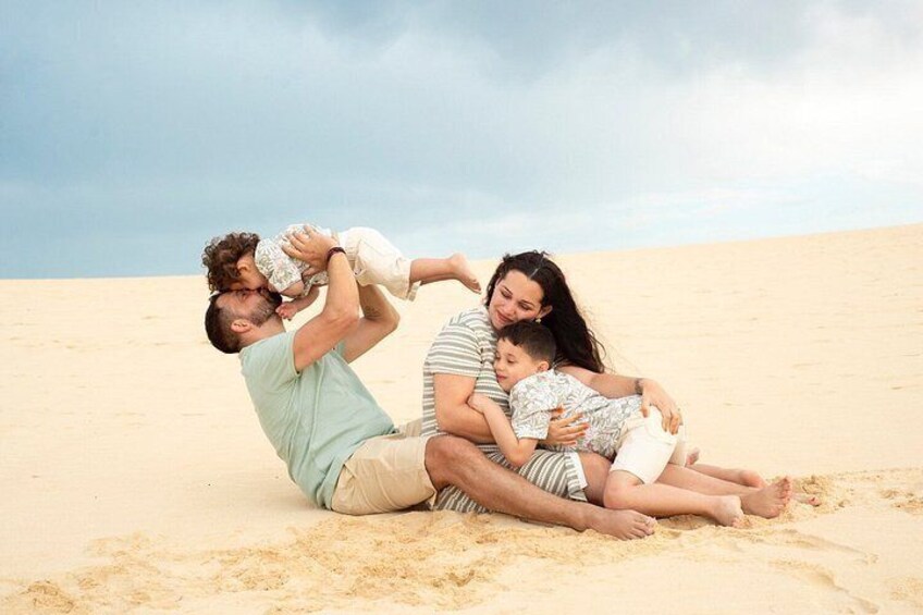A family of four on a sandy beach with a clear sky. 2