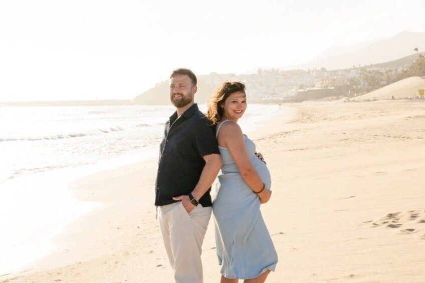 A couple standing on a beach with a mountain in the background. 3