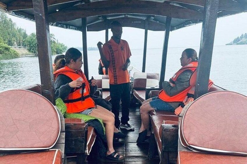 A boat with people wearing life jackets, a guide standing, and a calm body of water in the background. 4