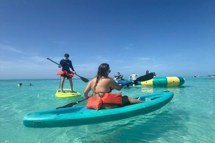Personas en kayak turquesa y tabla de remo en agua azul cristalina. 2