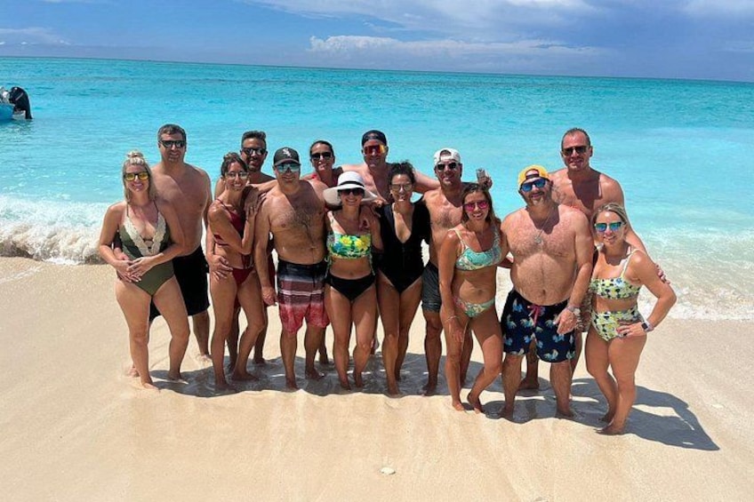 Een groep mensen op een zandstrand, met helder turquoise water op de achtergrond. 5