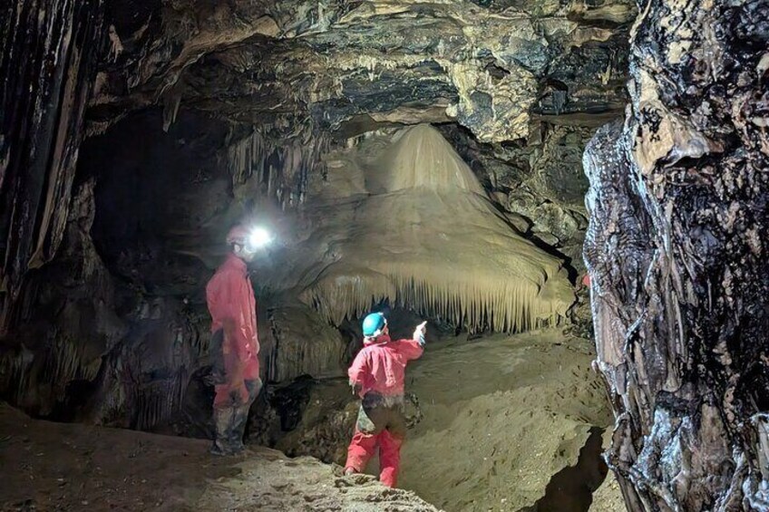 Deux personnes explorent une grotte ornée de stalactites et de stalagmites. 4