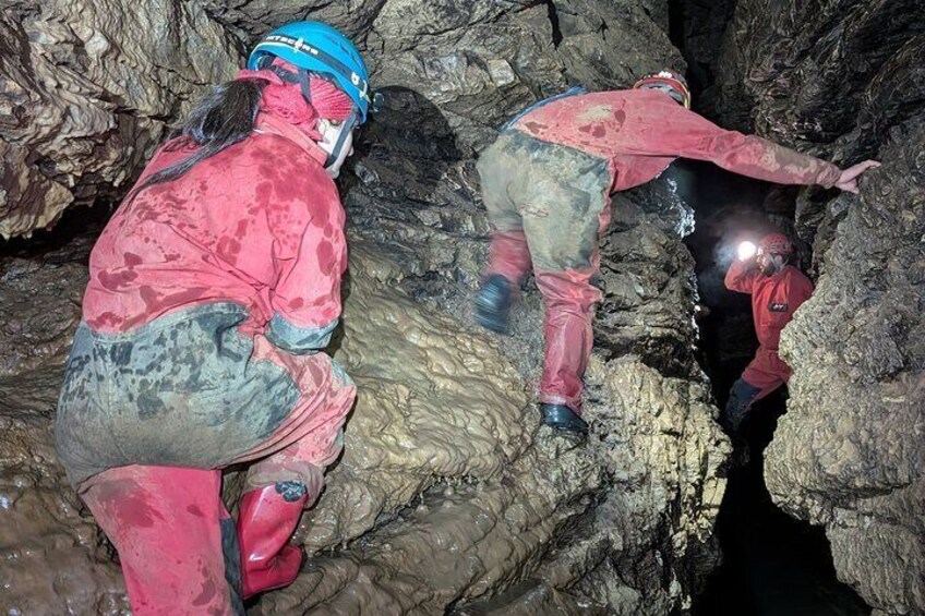 Deux personnes, vêtues d’équipements de protection rouges, explorent une grotte. 2