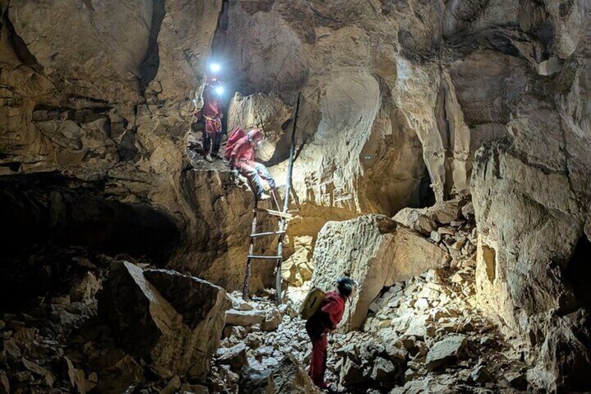 Des personnes se trouvent dans une grotte, avec une échelle, et explorent et examinent les parois rocheuses. 1