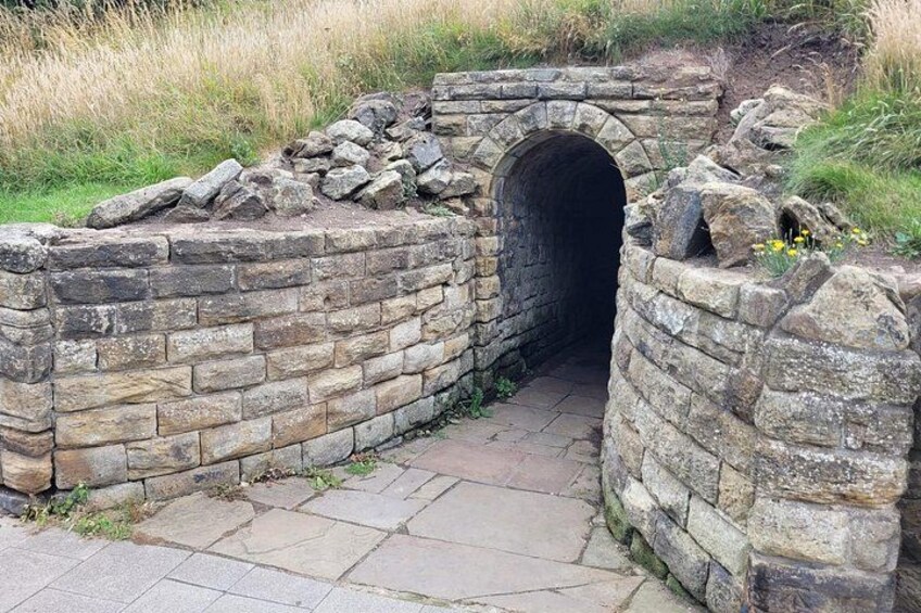 A stone tunnel entrance with a brick wall and a stone archway. 2