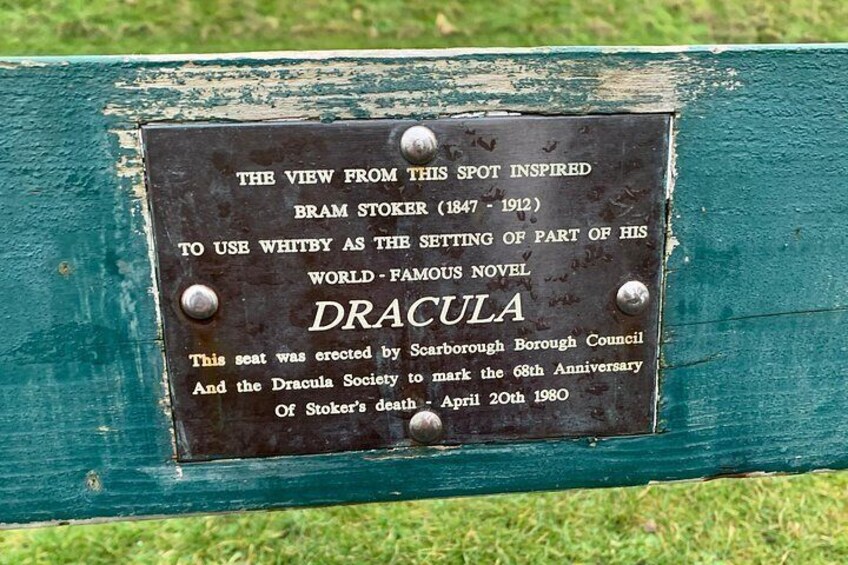 A plaque on a green-painted bench with a metal plate detailing Bram Stoker's inspiration for his novel Dracula. 3