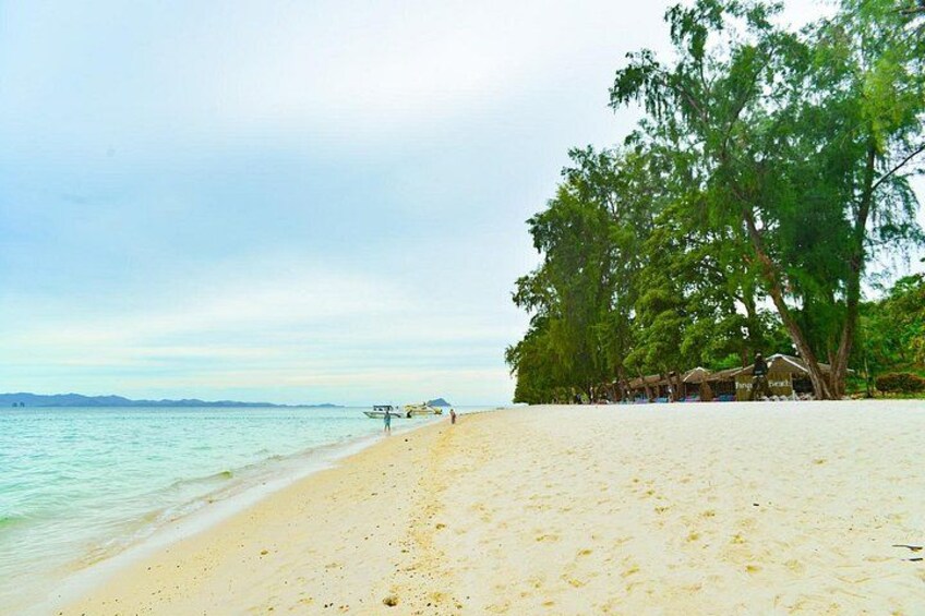 A beach with clear water, a sandy shore, and a row of thatched-roof huts. 5