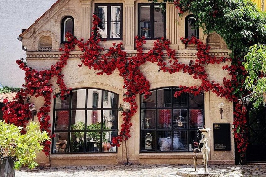 Un bâtiment orné de plantes grimpantes à fleurs rouges, doté de grandes fenêtres en arc de cercle et d’une statue devant l’entrée. 4