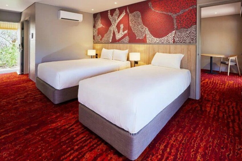 A hotel room with two beds, a red carpet, and a wall with a red and white design. 3