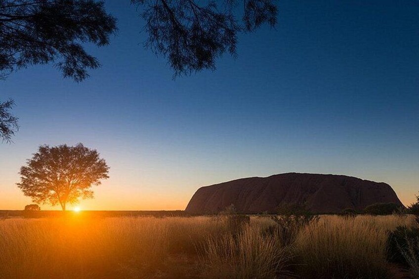 A large rock formation at sunset with a tree silhouetted against the sky. 5