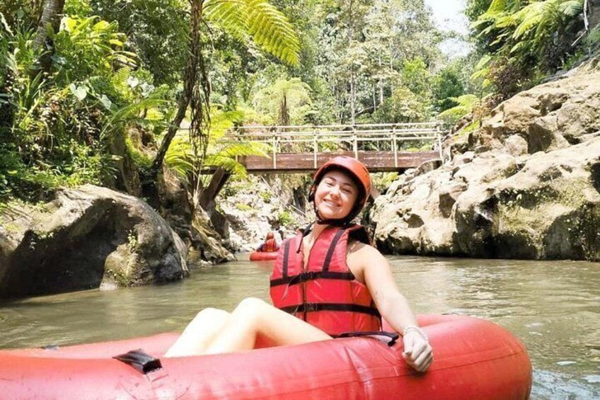 A person in a red raft on a river with rocks and greenery around. 1