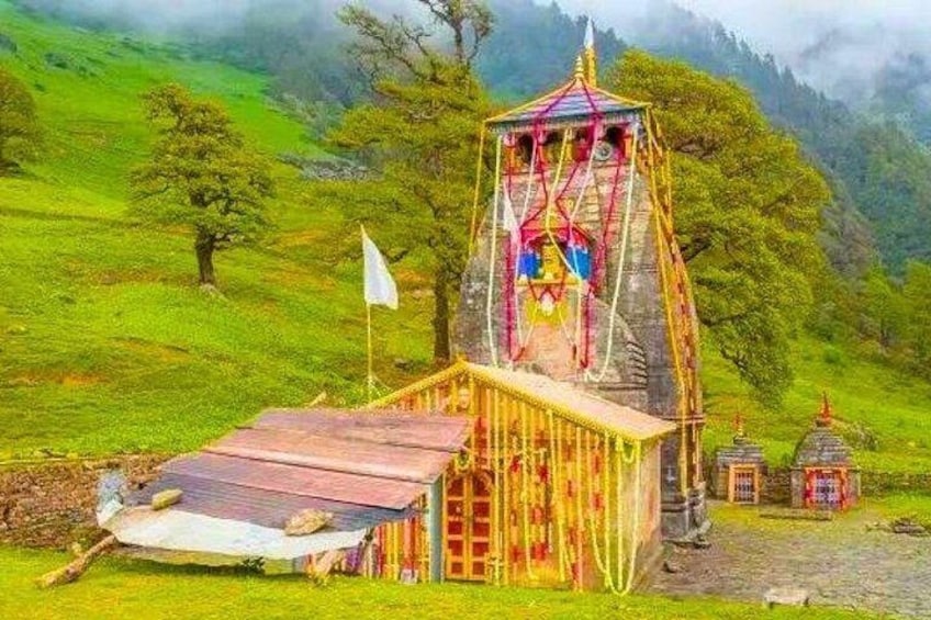 A temple with a colorful roof and a flag, surrounded by lush green hills and trees. 4