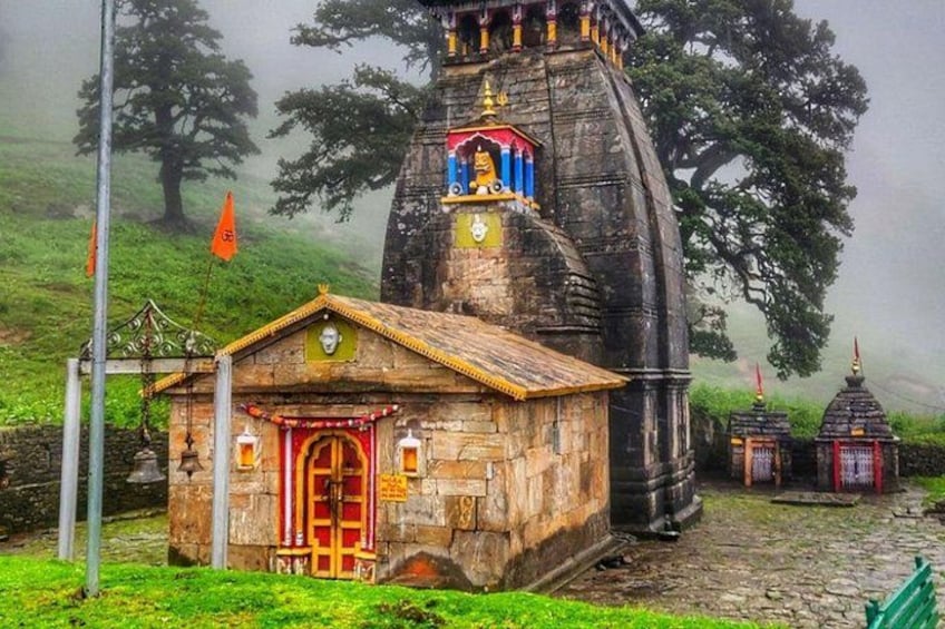 A stone structure with a red door, a small shrine, and a flag. 3