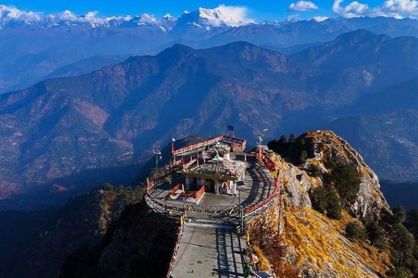 A temple on a mountain peak with a clear sky and snow-capped mountains in the background. 2