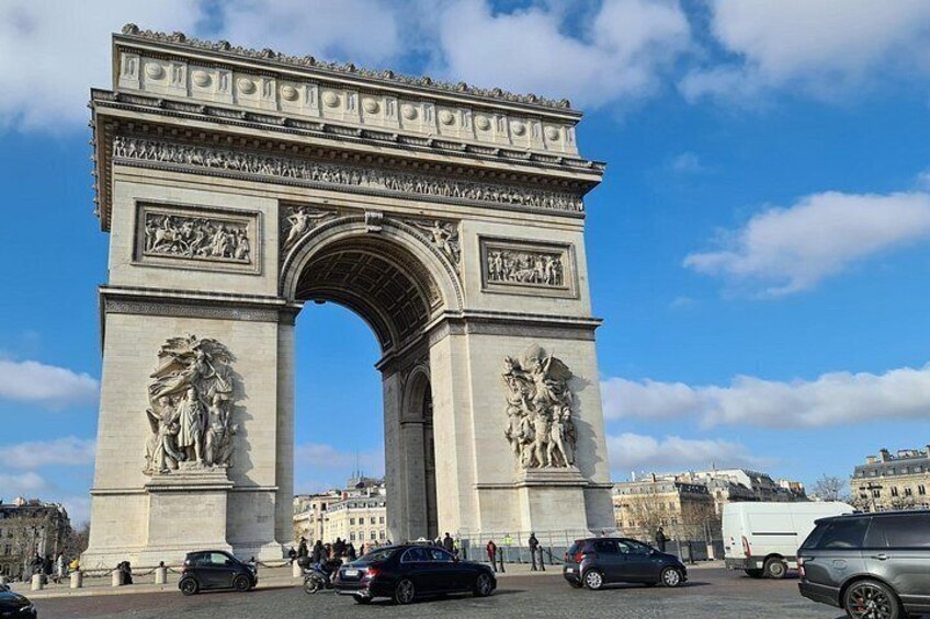 The Arc de Triomphe with a clear sky, surrounded by cars and buildings. 3
