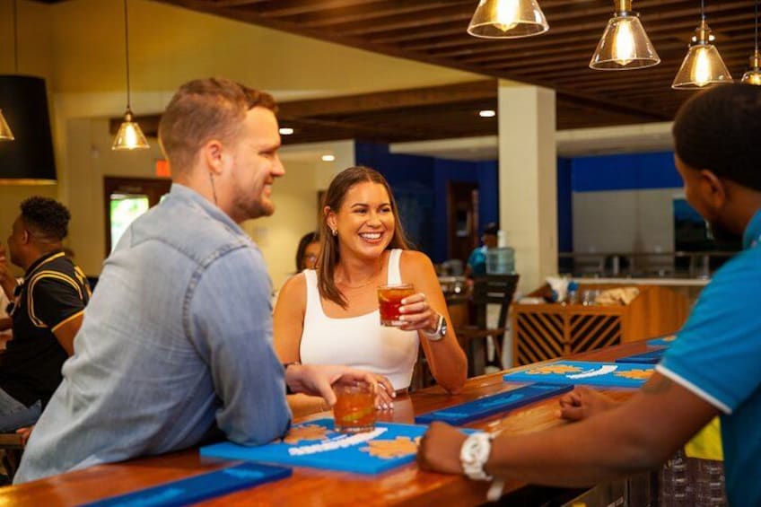 A bar with people sitting at tables, a bartender, and hanging pendant lights. 3