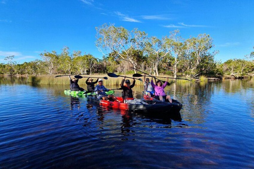 People kayaking on a calm river surrounded by trees. 5