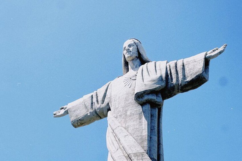 A statue with outstretched arms against a clear blue sky. 4