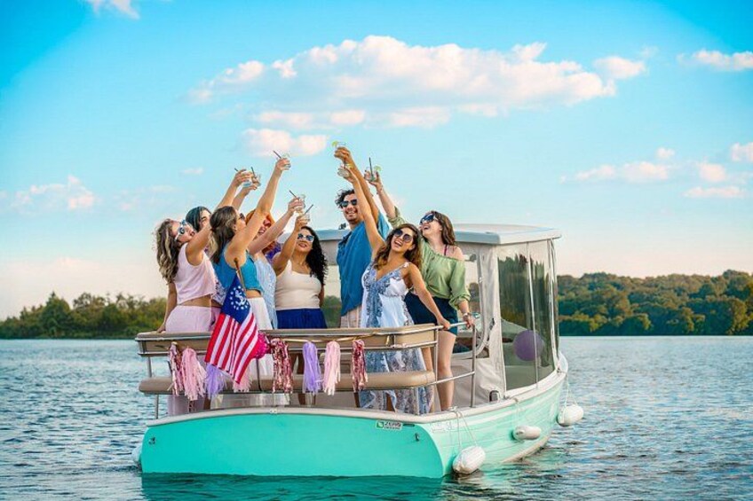 A group of people on a boat with an American flag, surrounded by water and trees. 3