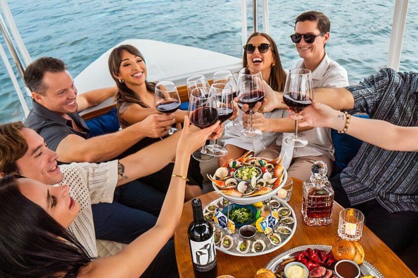 A group of people toasting with wine glasses on a boat, surrounded by food and drinks. 5