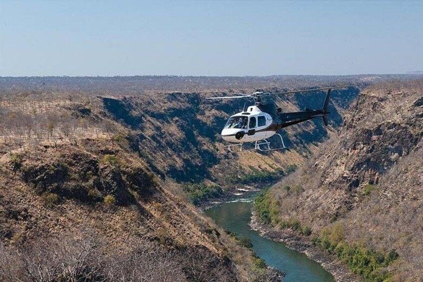 A helicopter flying over a canyon with a river. 3