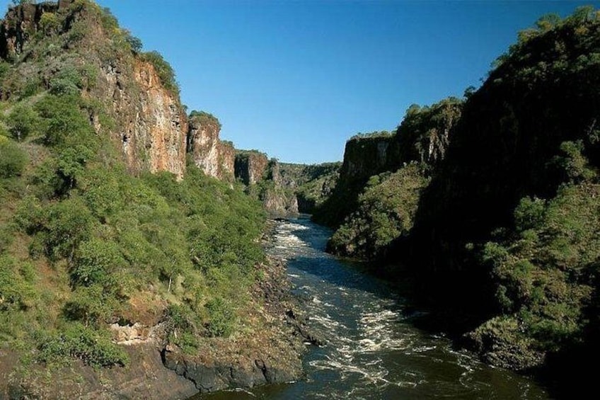 A river flowing through a canyon with steep cliffs and dense vegetation. 5