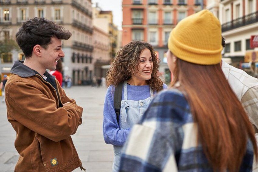 Three people standing on a city street with buildings in the background. 5