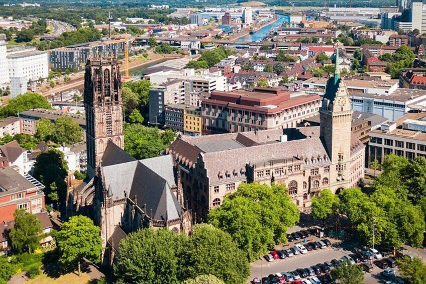 A cityscape with a prominent church featuring a tall tower and a large building with a green roof. 2