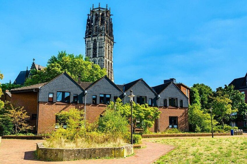 A church with a tall tower, surrounded by residential buildings and greenery. 3