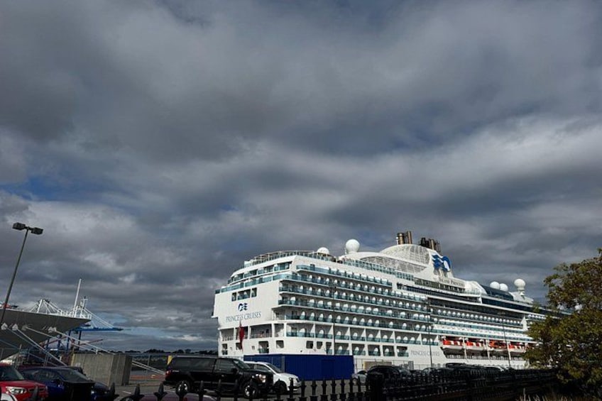 A large cruise ship docked at a port with a cloudy sky. 2