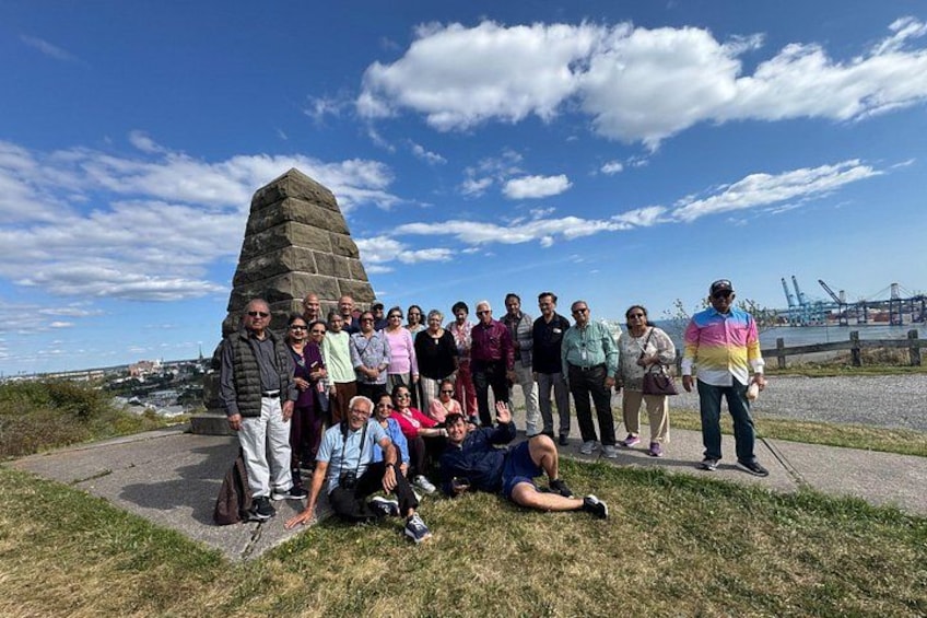 A group of people gathered around a stone monument on a sunny day. 1