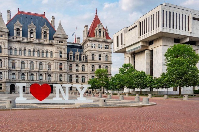 Een historisch gebouw met een rood dak, een modern constructie met verticale lijnen, en een hartvormig 'I ♥ NY' bord. 2