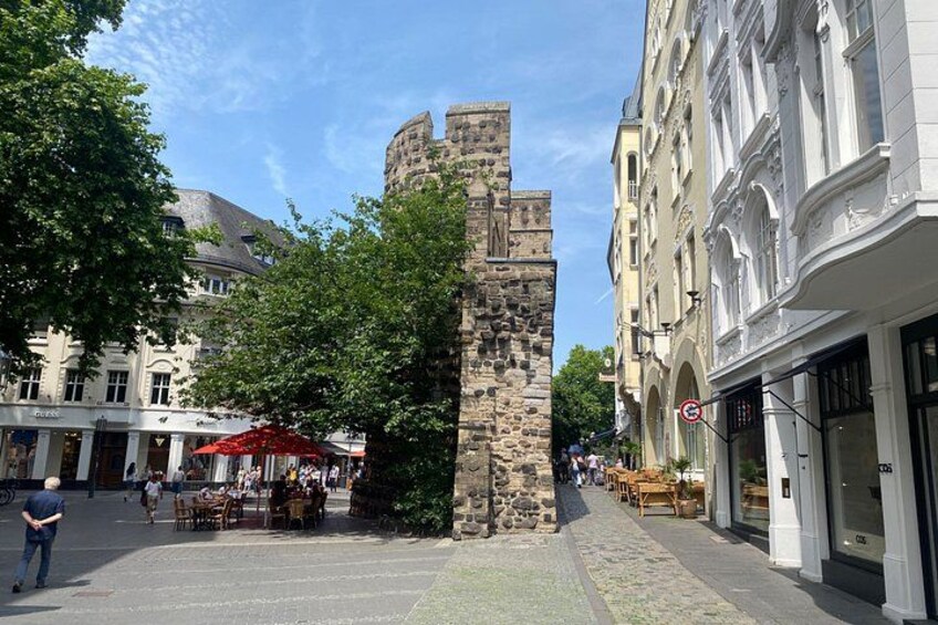 Et stenhus, en brostensbelagt gade og en café med udendørs siddepladser. 4