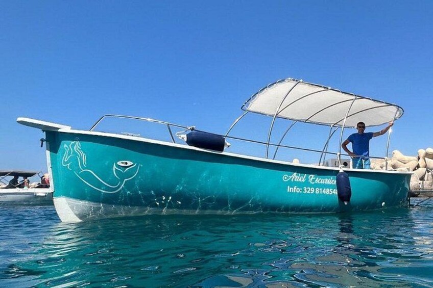 Ein türkisfarbenes Boot mit weißem Verdeck liegt in klarem, blauem Wasser vor Anker. 1