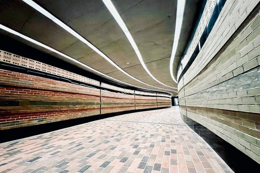 A subway station with tiled floors, brick walls, and overhead lighting. 4