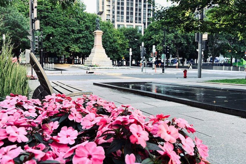 Un parc avec des fleurs roses, une statue et une fontaine. 2