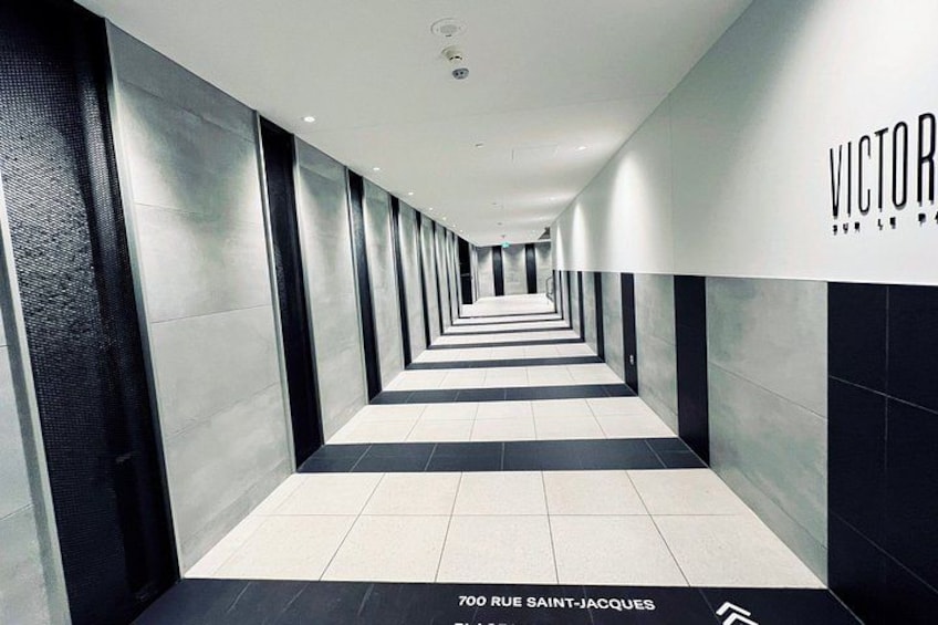 A modern hallway with a reflective floor, black and white walls, and a sign reading 'VICTOR'. 2