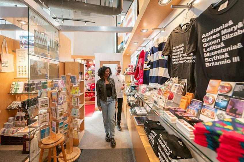 En boghandel med reoler fyldt med bøger og magasiner, et udstillingsvindue med farverige sokker, og en sort T-shirt med navne på. 4