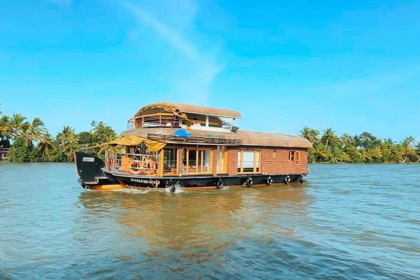 A houseboat on water with a thatched roof and wooden walls, surrounded by palm trees. 5