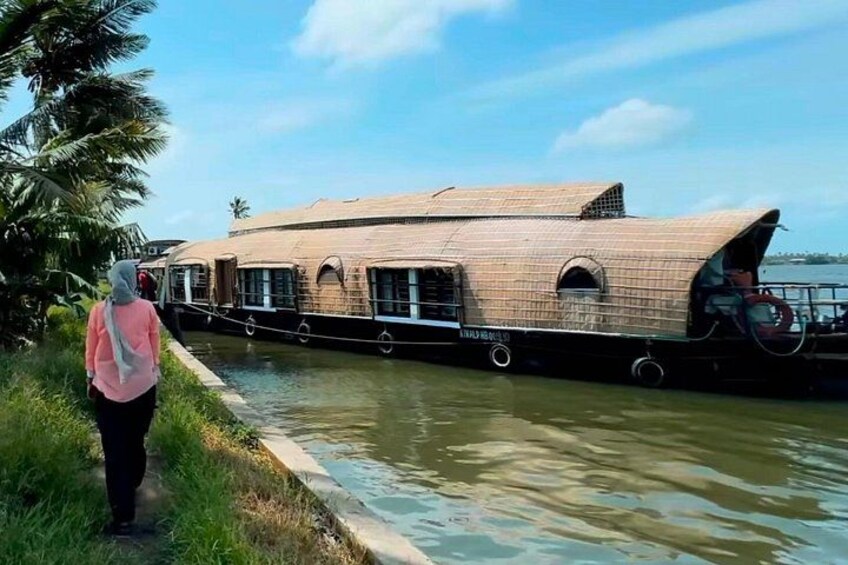 A houseboat on a river with a person standing by the shore. 4