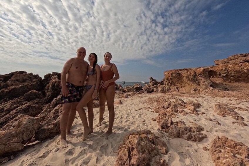 A rocky beach with three people standing. 5
