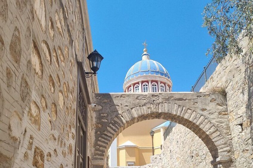 A stone archway, a building with a dome, and a clear blue sky. 1